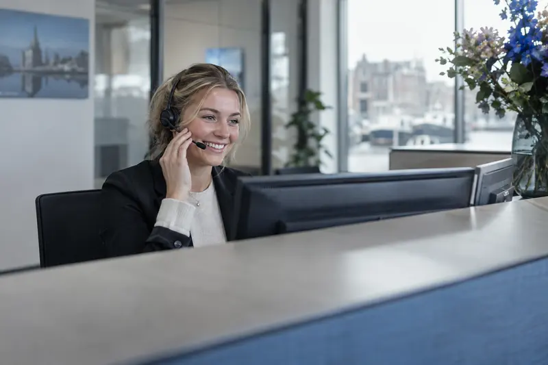 Receptioniste met een headset achter een bureau